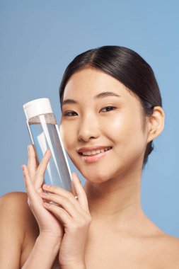 İzole edilmiş arka planda nemlendiricisi olan güzel Asyalı kadın portresi. 