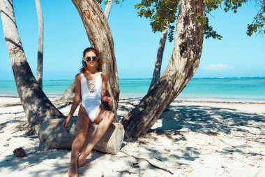 Genç ve güzel bir kadın sahilde dinleniyor.