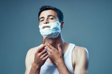 Stüdyo çekimi. Genç yakışıklı adam tıraş oluyor. 