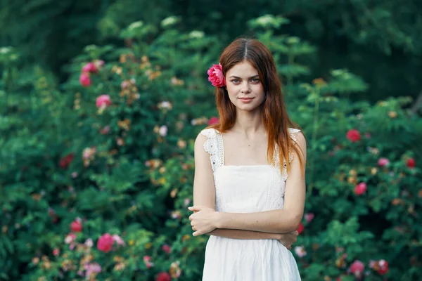 花园里开着红花的年轻漂亮的女人 — 图库照片
