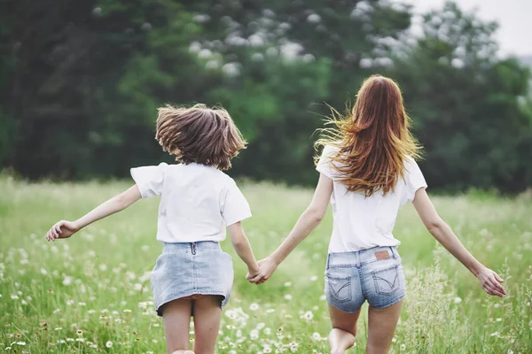 Genç anne ve kızı papatya tarlasında eğleniyorlar.