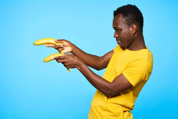 Young african man  pointing with bananas  isolated on blue background