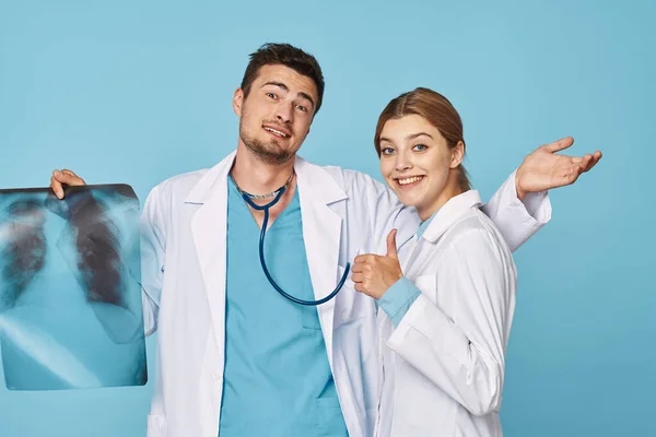 Studio shot. Young doctor and nurse with x-ray, doctor with thumb up