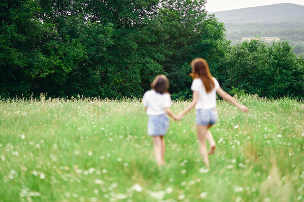 Young mother and her daughter having fun on camomile field