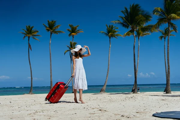 young beautiful woman with suitcase on tropical beach