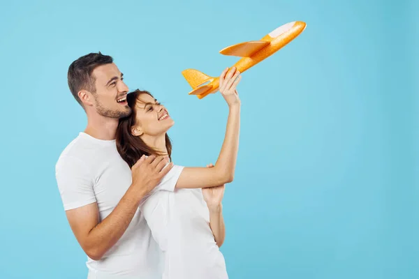 young  couple with toy airplane  in studio, isolated background