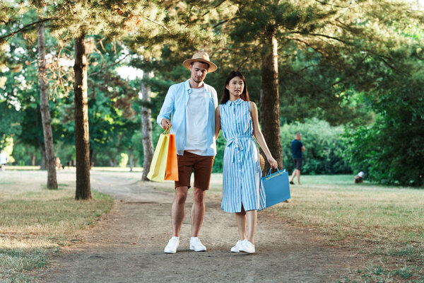 young couple with shopping bags walking  in the park. 
