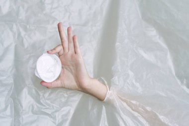 Plastik ve polietilen yırtıklar olan bir kadın eli.