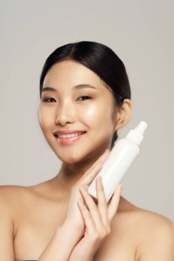 Güzel Asyalı kadın güzellik ürünlerini izole ediyor. 