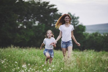 Genç anne ve kızı papatya tarlasında eğleniyorlar.