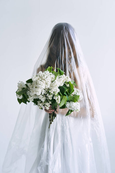 Young woman covered with polyethylene holding flowers