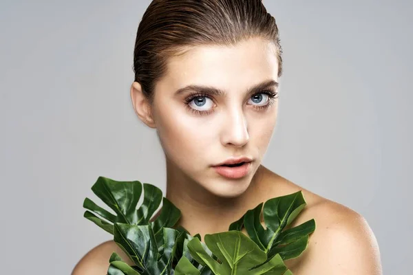 Young beautiful woman with leaves ain studio