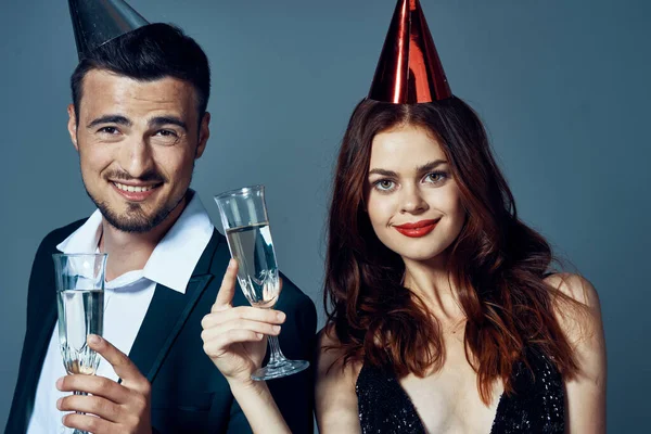 演播室拍摄的一对戴着派对帽的年轻漂亮夫妇用香槟庆祝圣诞节的照片 — 图库照片