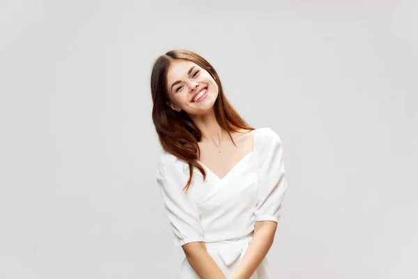 Mulher com um grande sorriso em um vestido branco inclinou a cabeça para uma visão recortada lado — Fotografia de Stock