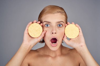 Çıplak omuzlu, sarışın, çıplak tenli, çıplak omuzlu, krem kaplıca salonu, gri arka plan.