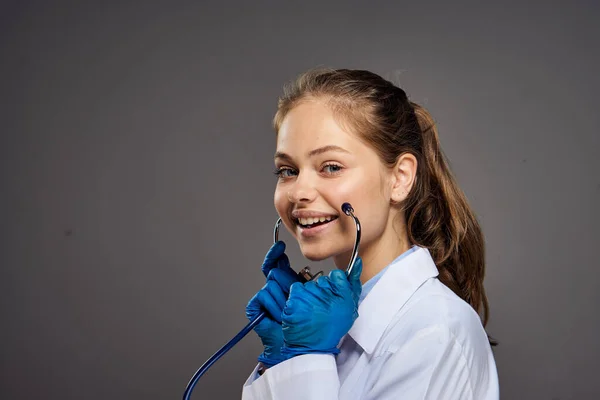 woman doctor in medical gown with stethoscope around her neck syringe injection eyeglasses intern gray background