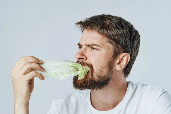 Hombre sentado a la mesa comiendo verduras saludables camiseta blanca dieta fondo claro — Foto de Stock