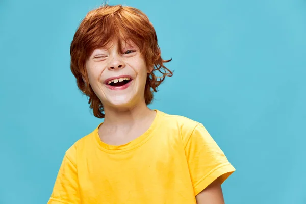 Menino de cabelo vermelho rindo no fundo isolado em uma camiseta amarela — Fotografia de Stock