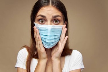 Tıbbi maskeli ürkek kadın elleriyle ve koronavirüsle yüzüne dokunuyor. 