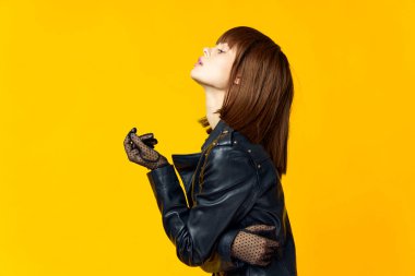 Siyah elbiseli ve eldivenli, parlak sarı arka planda bir kadın.