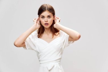 Şaşırmış yüz ifadesi olan bir kadın. Beyaz elbiseli, yüzü olan bir kadın. 