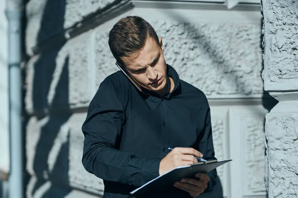 Homem de negócios com uma camisa perto do edifício com documentos nas mãos — Fotografia de Stock