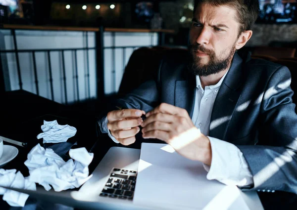 Homme d'affaires dans un café assis à la table documents ordinateur portable papier froissé style de vie exécutif émotions — Photo