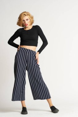 Siyah kazaklı, çizgili pantolonlu, güzel bir kadın. Moda kıyafetleri arka planda.