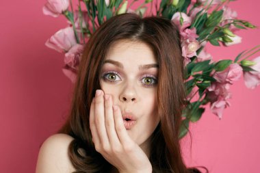 Başında çiçekler olan kadın. Duyguları çelenk olan. Eğlenceli pembe arka plan portresi. 