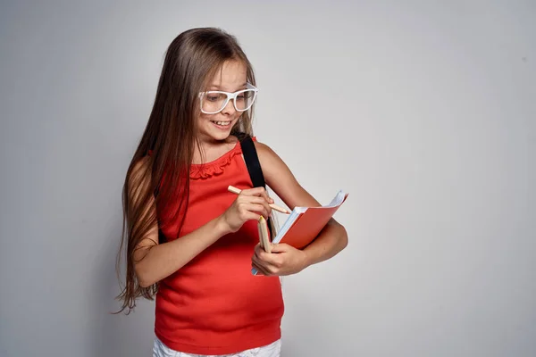 手で鉛筆で眼鏡の女の子学校教育赤Tシャツ — ストック写真