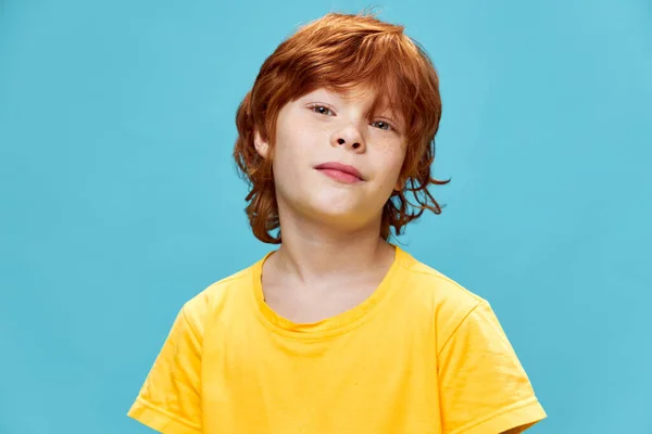 Rudowłosy chłopiec w żółtej koszulce na niebieskim tle — Zdjęcie stockowe