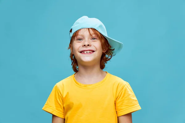 Gul T-shirt mössa på huvudet pojke blå bakgrund — Stockfoto