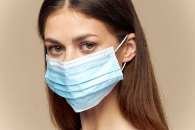 Tıbbi maske takan kadın yüzü, sağlık modeli bej arka plan portresi 