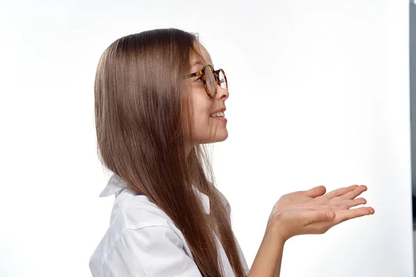 Девушка в белой рубашке и очках жесты с эмоциями рук светлый фон студии — стоковое фото