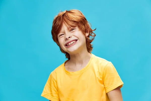 Ein Kind mit roten Haaren entblößte seine Zähne und schielte mit den Augen vor blauem Hintergrund — Stockfoto