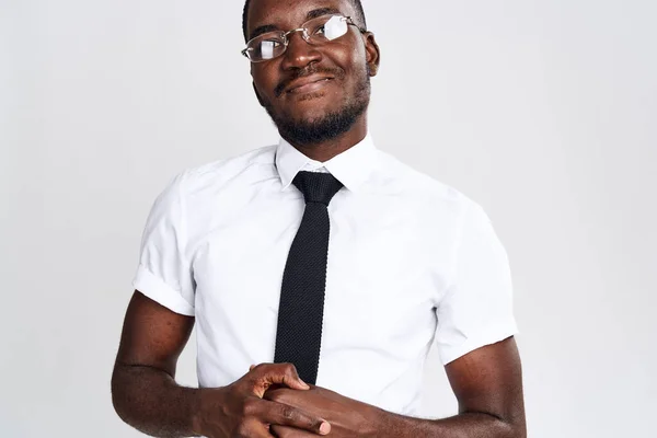 An African man in a shirt and tie on a light background gestures with his hands Copy Space — Stock Photo, Image