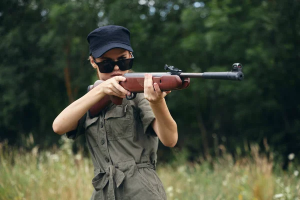 Frau an der frischen Luft zielt mit Waffen in grüne Blätter — Stockfoto
