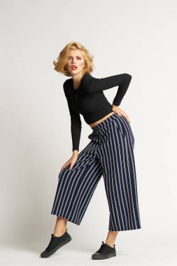 Siyah kazaklı, çizgili pantolonlu, güzel bir kadın. Moda kıyafetleri arka planda.