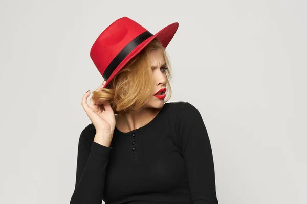 Fashionable woman in red hat black blouse red lips cropped view light background emotions