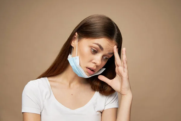 Indignant woman touches her face with hand and medical mask