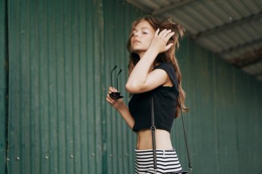 Siyah tişörtlü bir kadın şehir bardaklarının etrafında bir mankenin elinde yürüyor. 