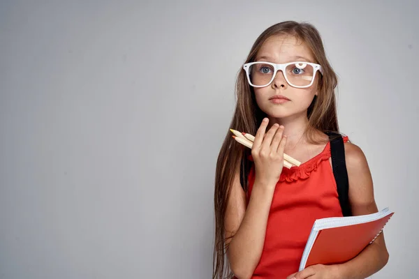 手で鉛筆で眼鏡の女の子学校教育赤Tシャツ — ストック写真