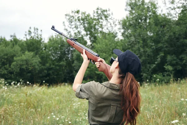 Mujer al aire libre sosteniendo una pistola a la vista cazando hojas verdes — Foto de Stock