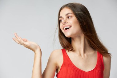  Kırmızı tişörtlü mutlu bir kadın arka planda elini yan tarafa uzatıp Boşluğu kopyaladığını gösteriyor.