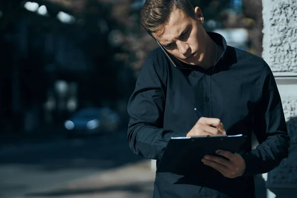 Homem de negócios com uma camisa perto do edifício com documentos nas mãos — Fotografia de Stock