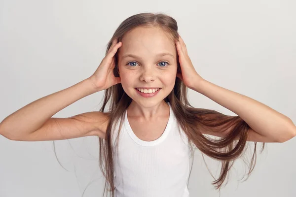 Veselá dívka v bílém tričku úsměv dlouhé vlasy close-up světlo pozadí oříznuté — Stock fotografie