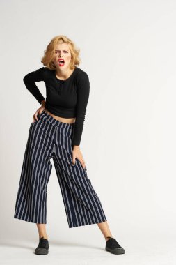 Siyah kazaklı, çizgili pantolonlu, güzel bir kadın. Moda kıyafetleri arka planda.