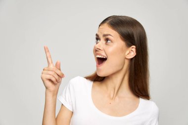 Beyaz tişörtlü bir kız ağzını açıp boşluğu dolduruyor.