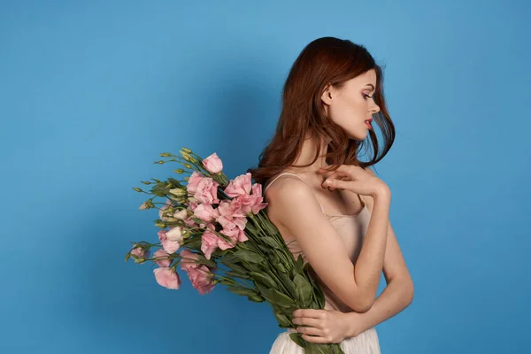 Piękna kobieta z bukietem różowych kwiatów na niebieskim tle model wiosna — Zdjęcie stockowe