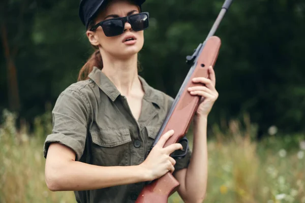 Mujer en la caza al aire libre con un arma en sus manos hojas verdes — Foto de Stock